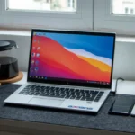 Notebook aberto sobre mesa de trabalho com mousepad, xícara de café e planta ao fundo — guia como escolher um notebook em 2026